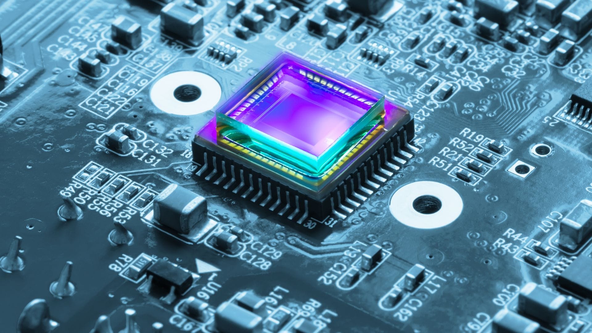 Close-up of a colorful image sensor or microchip mounted on a circuit board, surrounded by electronic components.